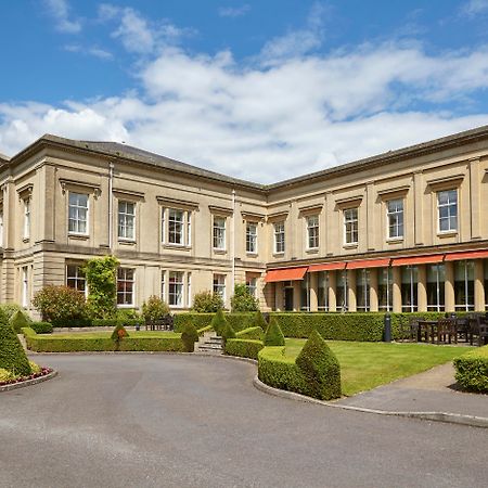 Macdonald Bath Spa Hotel Екстер'єр фото The photo depicts a large, elegant building with a classic architectural style, featuring a combination of stone and large windows. The structure appears to have two sections: a main, stately part on the left and an adjoining section that has a terra
