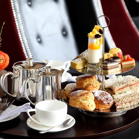 Macdonald Bath Spa Hotel Екстер'єр фото The photo depicts an elegantly arranged afternoon tea setting. There is a tiered stand filled with a variety of treats, including scones, sandwiches, and small desserts like cakes and pastries. Accompanying this is a teapot and a cup on the table, su