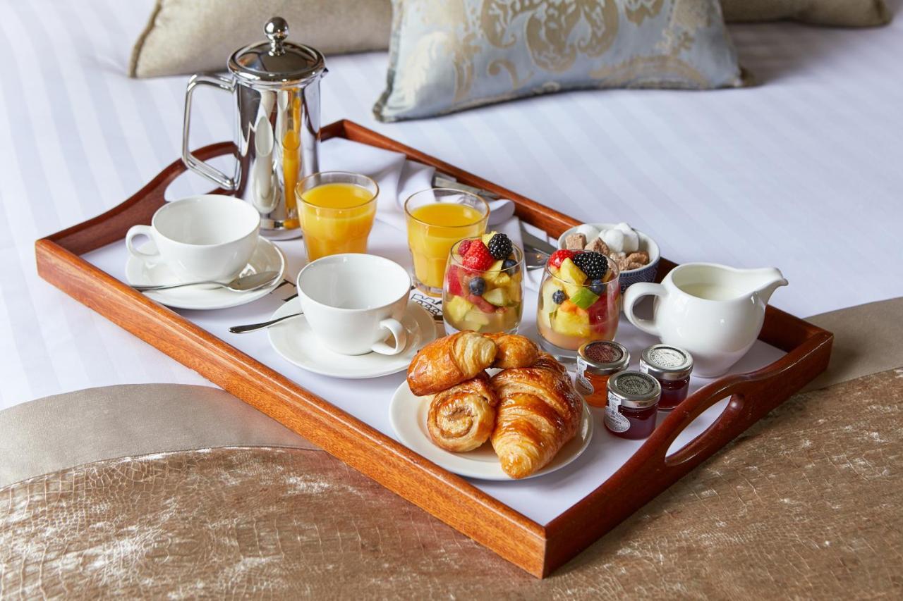 Macdonald Bath Spa Hotel Екстер'єр фото The photo shows a wooden tray arranged with a delightful breakfast spread. On the tray, there are two cups, a coffee pot, and several glasses of orange juice. There's also a small bowl of mixed fruit, featuring various colorful pieces. Additionally, 