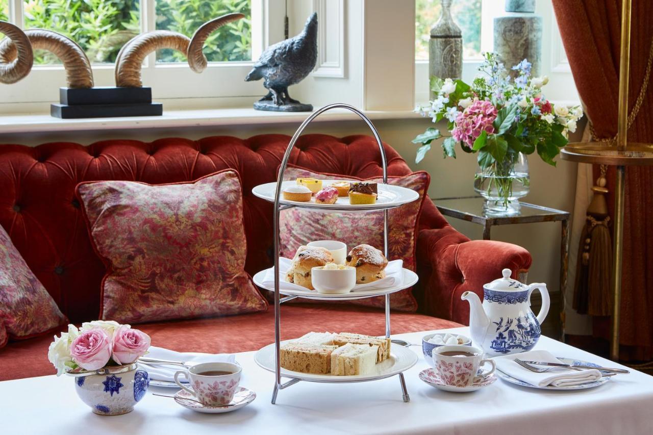 Macdonald Bath Spa Hotel Екстер'єр фото The photo showcases an elegant afternoon tea setting. In the foreground, there is a three-tiered serving stand filled with various pastries and scones, including some topped with cream and fruit. Surrounding the stand is a beautifully arranged table 