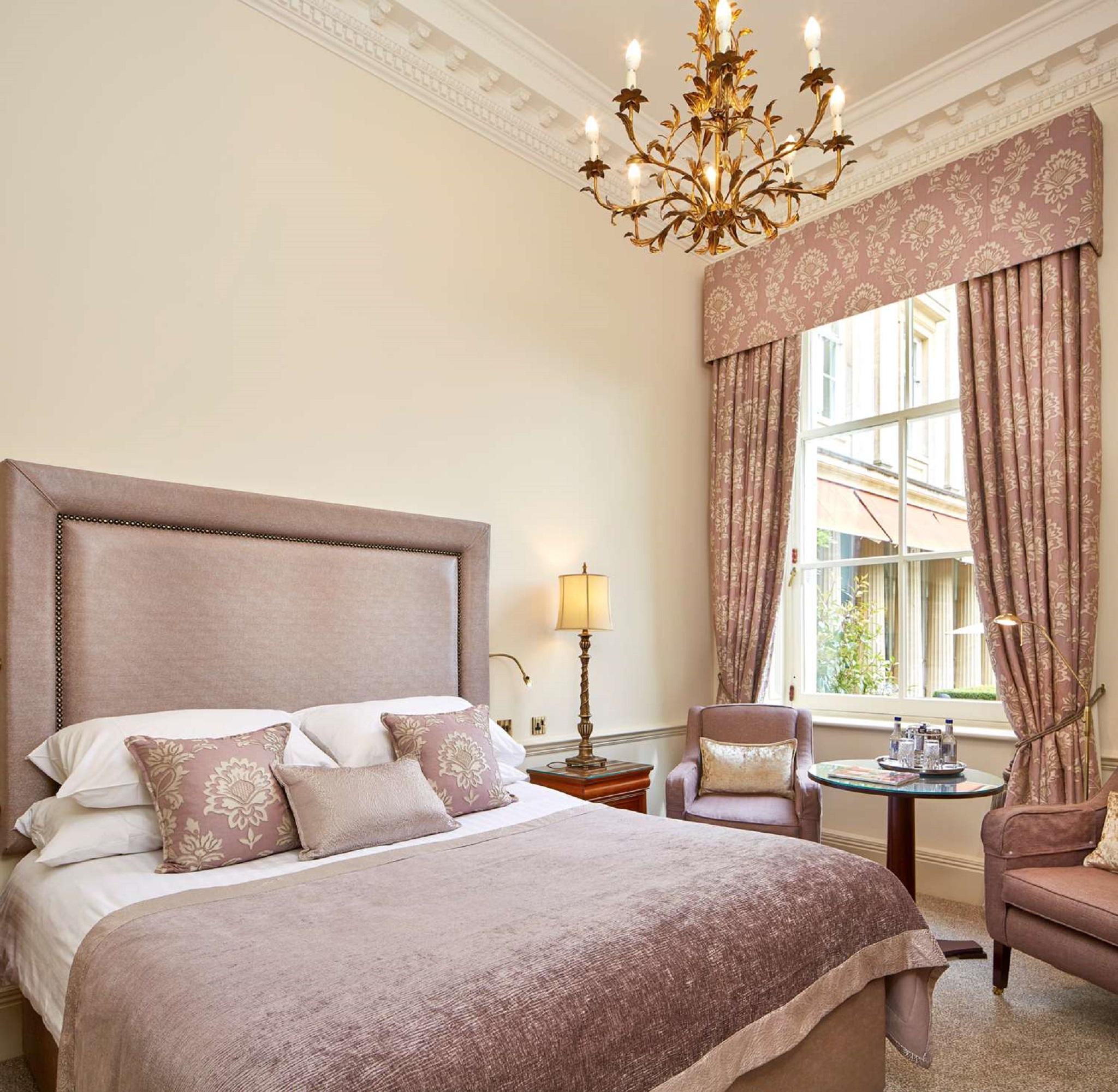Macdonald Bath Spa Hotel Екстер'єр фото The photo shows a beautifully decorated hotel room. It features a large bed with a plush headboard, adorned with several decorative pillows. The walls are painted in a soft color, and there is a chandelier hanging from the ceiling. Natural light come