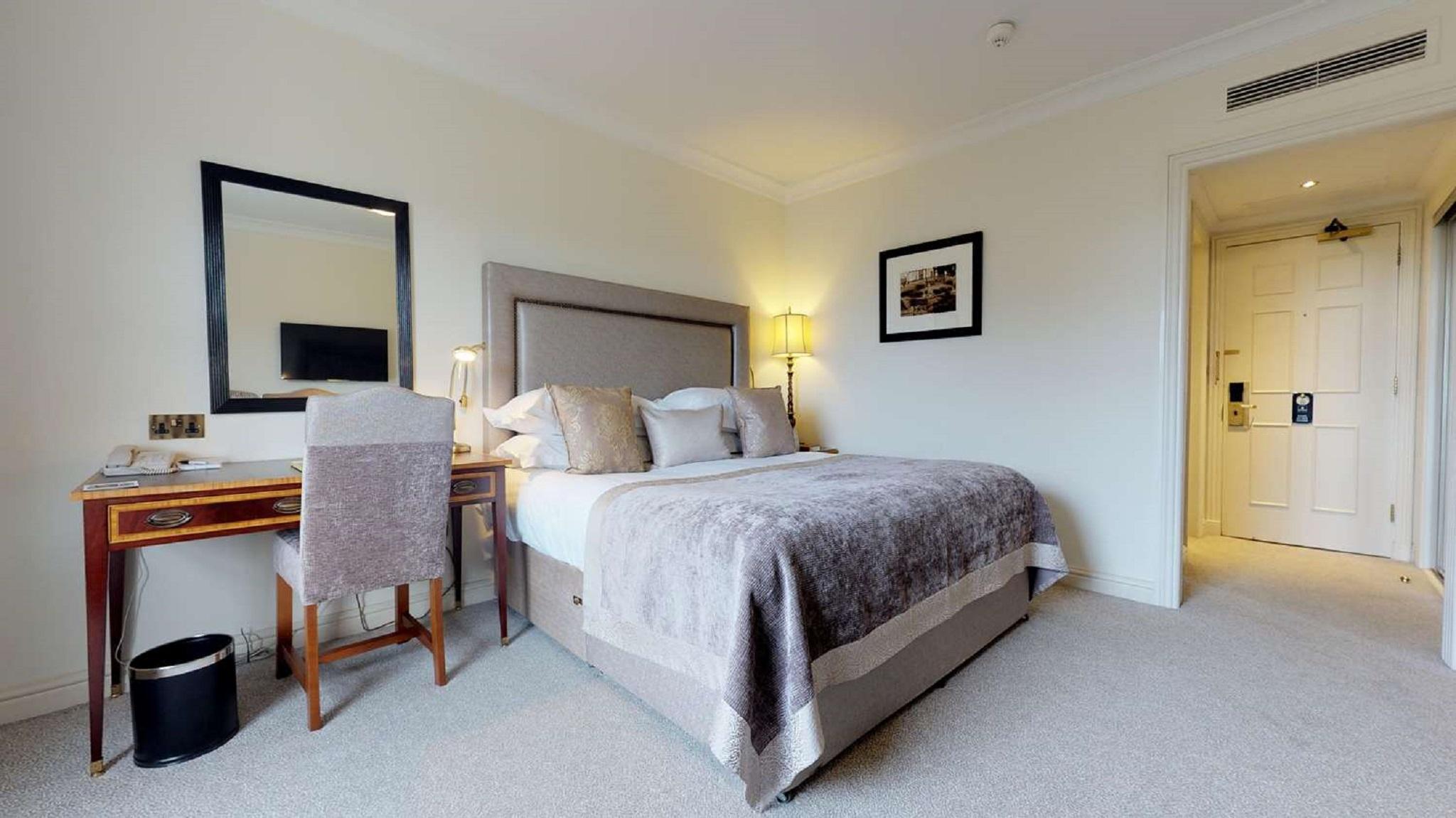 Macdonald Bath Spa Hotel Екстер'єр фото The photo shows a well-decorated hotel room. In the center, there's a comfortable bed with plush bedding and decorative pillows. A bedside table with a lamp is positioned next to the bed. To the left, there's a small desk with a chair, accompanied by