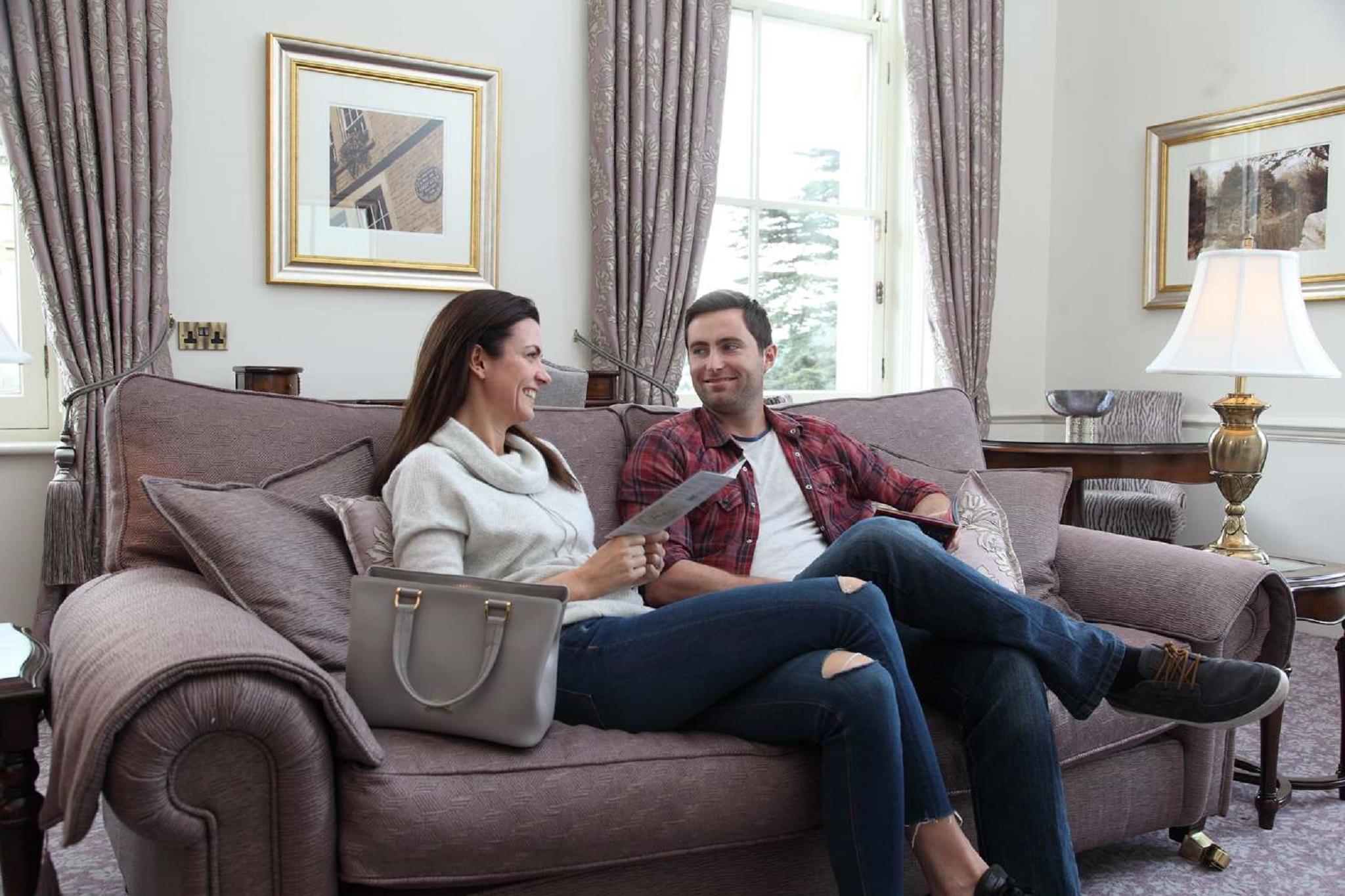 Macdonald Bath Spa Hotel Екстер'єр фото The photo shows a man and a woman sitting together on a comfortable sofa in a well-decorated room. The woman is holding a piece of paper and appears to be engaged in conversation with the man, who is smiling in response. They are both dressed casuall