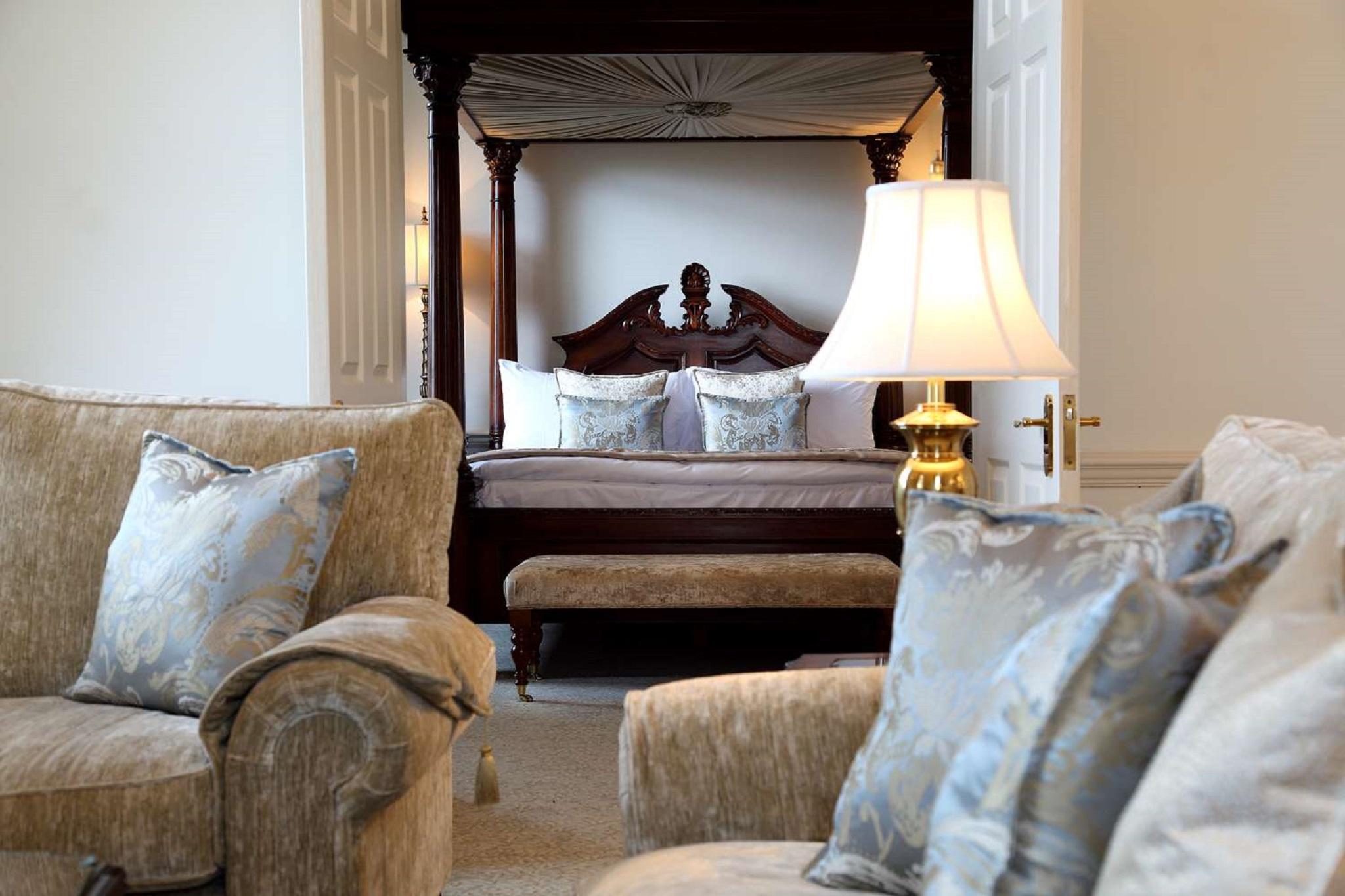 Macdonald Bath Spa Hotel Екстер'єр фото The photo shows a beautifully decorated room featuring a four-poster bed in the background. The bed has a wooden frame with a rich design, and it is adorned with plush bedding and pillows. In the foreground, there are comfortable sofas with decorativ