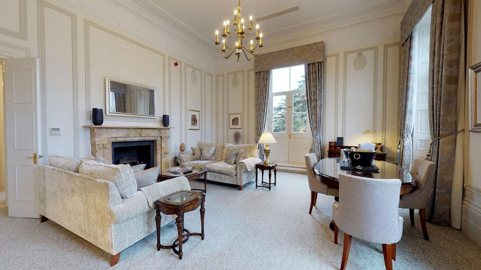 Macdonald Bath Spa Hotel Екстер'єр фото The photo shows an elegant living room with a classic design. It features a large chandelier hanging from the ceiling, providing soft lighting. The walls are adorned with decorative moldings and have a light color. 

In the center, there are two plus